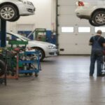 自動車整備工場で作業する整備士とリフトアップされた車両の様子